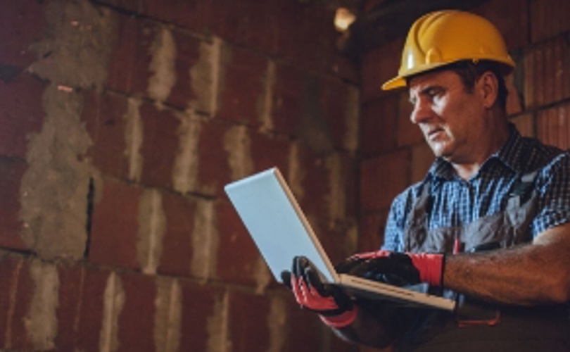 Man met laptop in de bouw